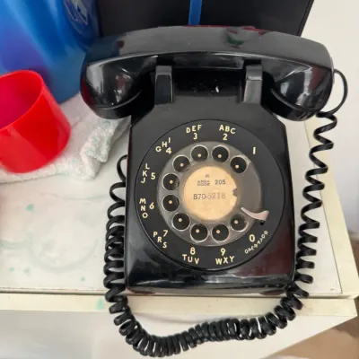 Sale Photo Thumbnail #212: Vintage black Western Electric Model 500 rotary desk telephone with coiled cord, displaying area code 205 on the central dial card.