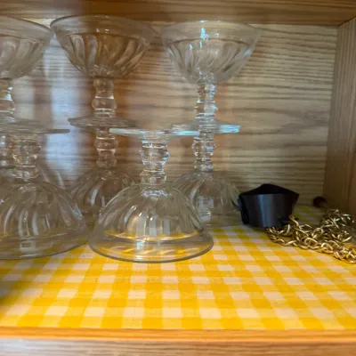 Sale Photo Thumbnail #241: Set of clear glass dessert cups with swirl optic details arranged inside a cabinet.