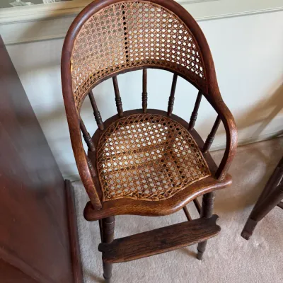Sale Photo Thumbnail #406: Antique bentwood high chair featuring woven cane backrest and seat panels with a turned spindle support frame.