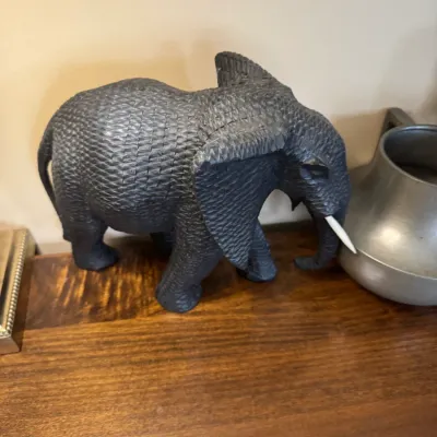 Sale Photo Thumbnail #43: Hand-carved dark wood elephant figurine with detailed crosshatch skin texturing and light-colored tusks.