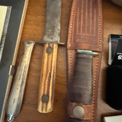 Sale Photo Thumbnail #21: Vintage fix-blade hunting knife with bone or stag scales, alongside a Western brand leather sheath containing a stacked leather handle knife.