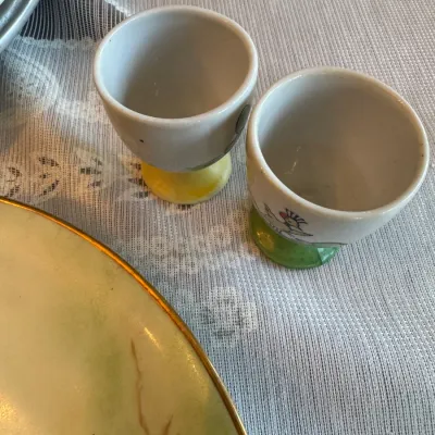 Sale Photo Thumbnail #418: Pair of vintage ceramic egg cups featuring hand-painted bird motifs on yellow and green bases.