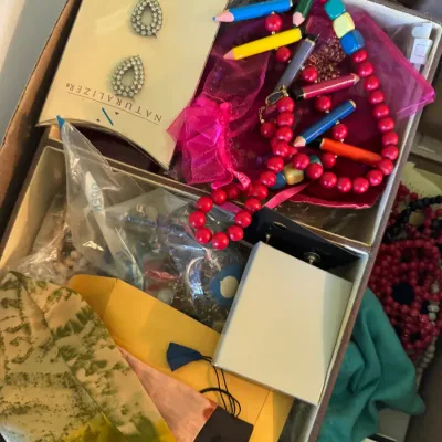 Sale Photo Thumbnail #58: Box filled with assorted costume jewelry and accessories, including a novelty colored pencil and red bead necklace, Naturalizer clip-on earrings, and various jewelry pouches.