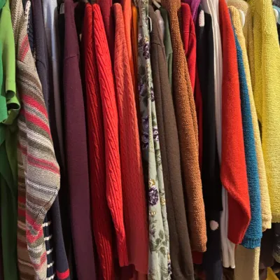 Sale Photo Thumbnail #152: Closet packed with vintage and contemporary knit sweaters, long-sleeve tops, and cardigans hanging closely on a rack.