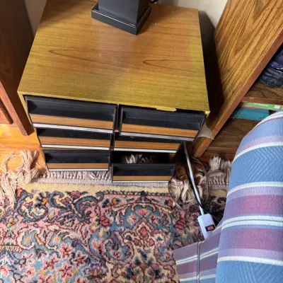 Sale Photo Thumbnail #300: Vintage woodgrain cassette tape storage cabinet with multiple drawered compartments sitting on a patterned rug.