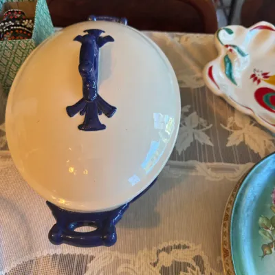 Sale Photo Thumbnail #420: Vintage ceramic covered tureen featuring a glossy off-white glaze with deep blue handles and top finial.