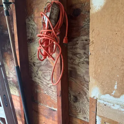 Sale Photo Thumbnail #190: Vintage caged trouble light with an orange extension cord hanging on a workshop wall alongside a Werner aluminum ladder.