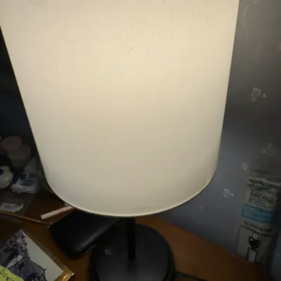 Sale Photo Thumbnail #173: Modern black metal table lamp featuring a round base and a tall, off-white cylindrical drum shade.