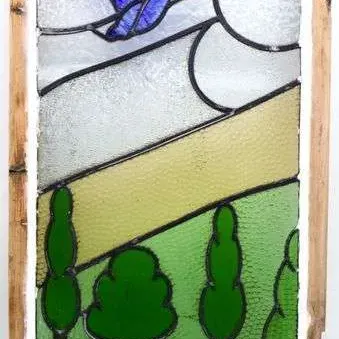 Sale Photo Thumbnail #15: Framed stained glass window panel featuring a bird flying over a rolling green landscape with trees, set in a rustic wooden sash frame.