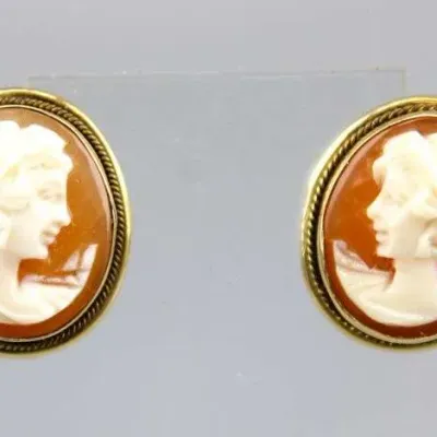Sale Photo Thumbnail #2: Pair of vintage oval cameo earrings featuring carved shell portrait profiles in twisted rope-edge gold-tone settings.