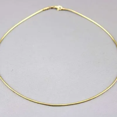 Sale Photo Thumbnail #24: Gold-tone omega chain necklace featuring a smooth, rigid band design with a standard lobster claw clasp.