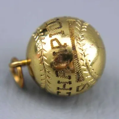 Sale Photo Thumbnail #8: Vintage gold-toned baseball charm with engraved seams and lettering, showing some wear.