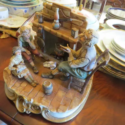 Sale Photo Thumbnail #25: Vintage Capodimonte porcelain figurine depicting an elderly man telling a story to two children by a fireplace, resting on an ornate gilded base.