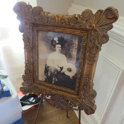 Sale Photo Thumbnail #47: Antique Edwardian-era portrait photo of a seated woman in an ornate, heavily carved gold-painted frame, displayed on a wrought iron floor easel.