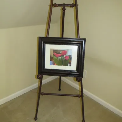 Sale Photo Thumbnail #85: Dark stained wood floor easel with turned finials holding a framed photograph of pink tulips.