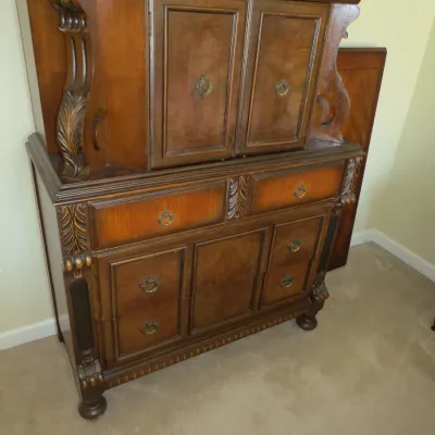 Sale Photo Thumbnail #76: Traditional dark wood hutch cabinet featuring carved scroll accents, brass drop handles, and multiple drawers and storage compartments.
