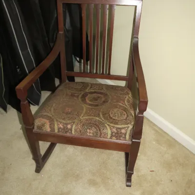 Sale Photo Thumbnail #83: Vintage dark stain wooden armchair featuring a slat back, curved armrests, and a patterned fabric seat cushion.