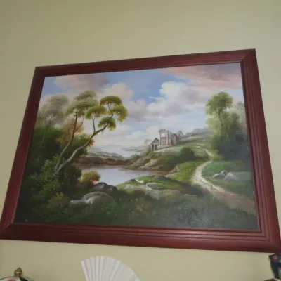 Sale Photo Thumbnail #36: Large framed oil painting depicting a pastoral landscape with a lake, classical ruins, and a winding path, presented in a dark reddish-brown wood frame.