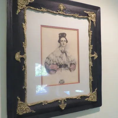 Sale Photo Thumbnail #71: Framed antique portrait print of a Victorian woman, set in a dark wood frame featuring ornate gilt brass or bronze corner mounts and trim.