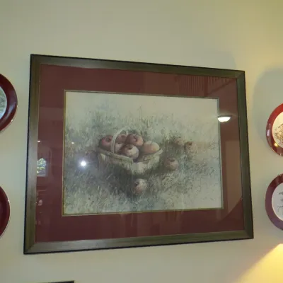 Sale Photo Thumbnail #32: Framed still life watercolor print depicting a basket of apples, flanked by four bird-themed decorative wall plates with dark red rims.