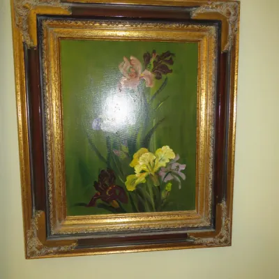 Sale Photo Thumbnail #88: Framed floral oil painting depicting colorful iris blooms against a dark green background, presented in an ornate gilt and wood frame.
