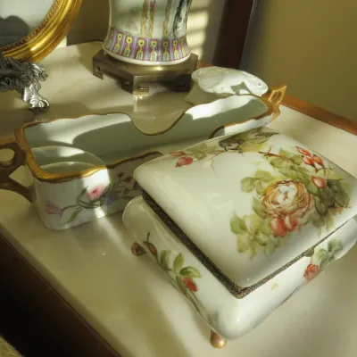 Sale Photo Thumbnail #10: Hand-painted porcelain items including a hinged trinket box featuring a bird's nest and rose motif alongside a gilded tray.