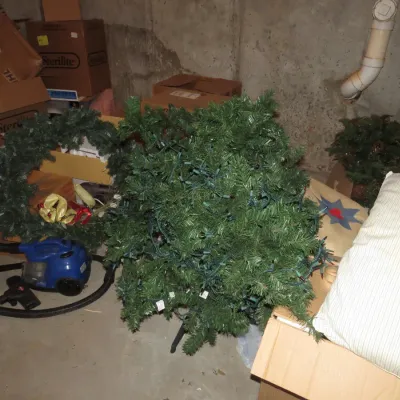 Sale Photo Thumbnail #48: Collection of holiday decorations and household items including a small pre-lit artificial Christmas tree, artificial green wreath, and a blue portable canister vacuum cleaner.