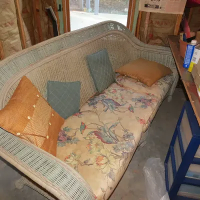 Sale Photo Thumbnail #56: Vintage wicker sofa painted light green, featuring floral upholstered seat cushions and a selection of throw pillows.