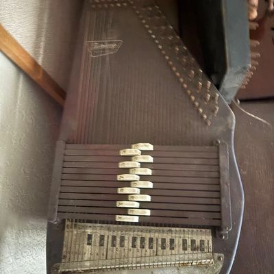 Sale Photo Thumbnail #60: Vintage Oscar Schmidt Autoharp stringed instrument with chord bars and printed note guide, showing light surface dust and wear.