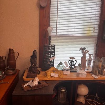 Sale Photo Thumbnail #13: A collection of tabletop decor and collectibles displayed on a wooden cabinet, including a horse statue lamp base, an abacus lamp, porcelain figurines, decorative glass, and metalware.