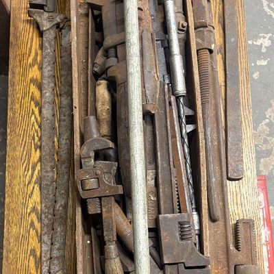 Sale Photo Thumbnail #63: Vintage wooden tool tote filled with rustic hand tools, including large pipe wrenches, adjustable wrenches, hand drills, and bar clamps.