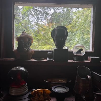 Sale Photo Thumbnail #12: Collection of eclectic windowsill decorative items including sculpted busts, snow globes, small figurines, and vintage copper and brass vessels.
