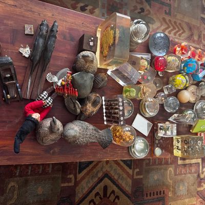 Sale Photo Thumbnail #10: Large collection of vintage trinkets and collectibles displayed on a wooden coffee table, including resin paperweights, carved wooden birds, figurines, and various glass objects.