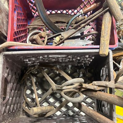Sale Photo Thumbnail #86: Collection of vintage hand tools, including ice tongs, scythes, and wooden-handled utensils, stored in plastic milk crates.