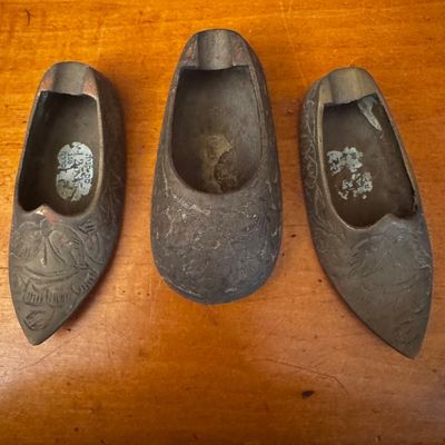 Sale Photo Thumbnail #46: Set of three vintage metal shoe-shaped ashtrays featuring carved floral and scroll designs.