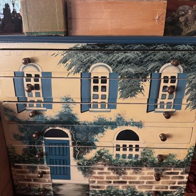 Sale Photo Thumbnail #11: Hand-painted tallboy dresser featuring a detailed house exterior motif across the drawer fronts, complemented by round wooden knobs.