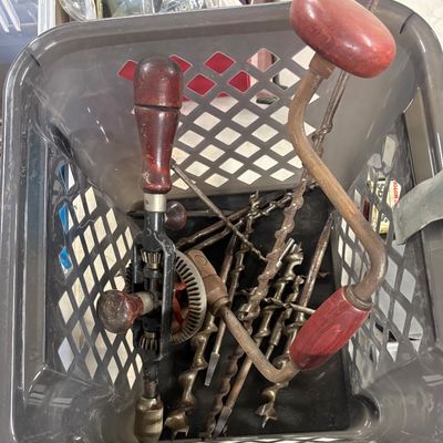 Sale Photo Thumbnail #79: Vintage hand drills, brace, and assortment of auger drill bits with reddish wood handles in a grey plastic tote bin.