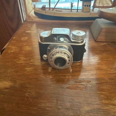 Sale Photo Thumbnail #52: Vintage Hit miniature subminiature camera with chrome trim and black leatherette body, made in Japan, circa mid-20th century.