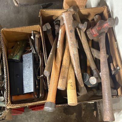 Sale Photo Thumbnail #83: Cardboard boxes filled with assorted vintage hand tools, including various hammers, mallets, and drafting instruments.