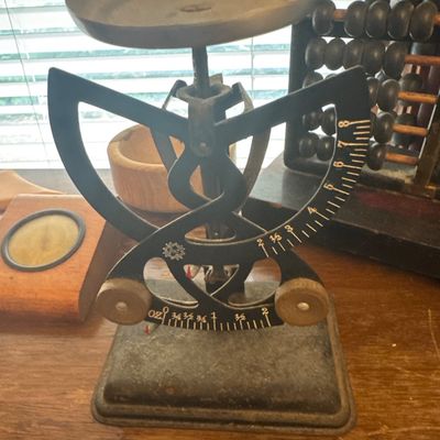 Sale Photo Thumbnail #36: Vintage Triner scale with a metal top tray, dual-beam balance design, and a heavy cast iron base, shown alongside a wooden abacus.