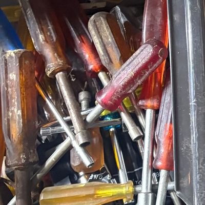 Sale Photo Thumbnail #77: Assorted vintage screwdrivers and hand tools with translucent acetate handles, stored in a black plastic bin.