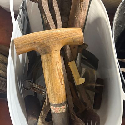 Sale Photo Thumbnail #66: Collection of vintage hand tools and garden implements stored in a white plastic basket, featuring wooden handles and weathered metal components.