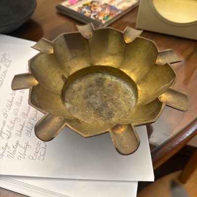 Sale Photo Thumbnail #25: Vintage brass flower-shaped ashtray with multiple cigarette rests, showing heavy patina and signs of use inside the bowl.