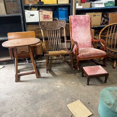 Sale Photo Thumbnail #56: Collection of vintage accent furniture, including a high-back pink plush upholstered rocking chair with matching footstool, an ornate carved wooden rocking chair, and a small round wooden table.