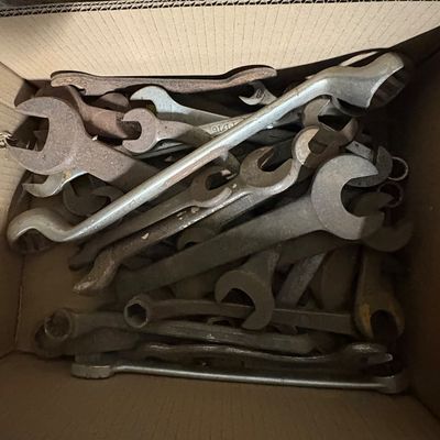Sale Photo Thumbnail #69: Cardboard box filled with assorted vintage hand tools, including various sizes of open-end and combination wrenches showing surface rust and wear.