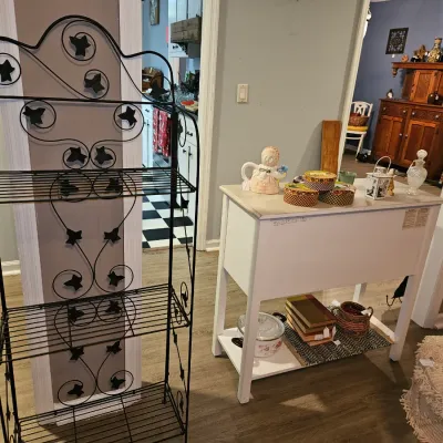 Sale Photo Thumbnail #57: Black wrought iron baker's rack with decorative ivy leaf scrollwork, shown next to a white two-tier kitchen island cart.