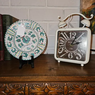 Sale Photo Thumbnail #27: Hand-painted Italian majolica rooster display plate shown alongside a rustic white metal alarm clock-style table clock.