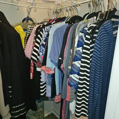 Sale Photo Thumbnail #25: Selection of women's contemporary clothing including sweaters, shirts, and jackets hanging in a closet.
