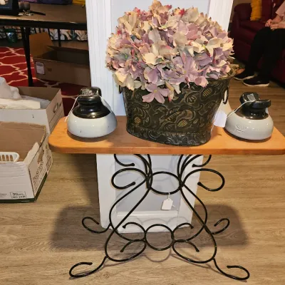 Sale Photo Thumbnail #58: Wrought iron side table with a wooden top, featuring a faux floral arrangement in an embossed planter and a pair of ceramic porcelain insulators.