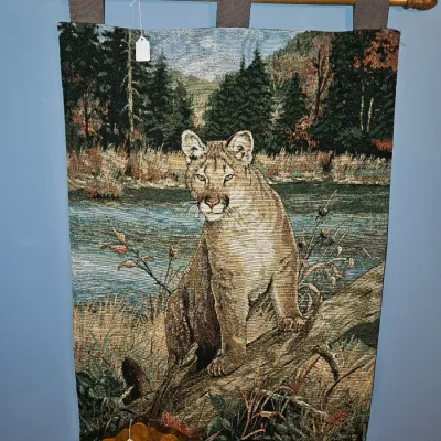 Sale Photo Thumbnail #36: Woven jacquard wall tapestry depicting a cougar in a forest setting, suspended from a wooden rod with finials.